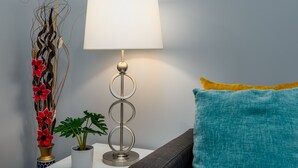 A modern lamp with a white shade, a decorative vase with red flowers, and a green plant on a white surface. - 3 Bedroom 3 Bath House  in Atlanta -Two Blocks To GWCC, Mercedes-Benz Stadium  (Atlanta)