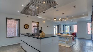 Een moderne keuken met een centraal eiland, grote ramen en een eethoek met uitzicht.