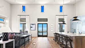 A spacious kitchen with a central island, bar stools, and a view through the glass door. - 283 Lakeview Drive (Seagrove Beach)