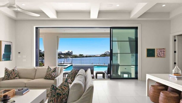 A modern living room with a sofa, coffee table, and a view of a pool and ocean. - 283 Lakeview Drive (Seagrove Beach)