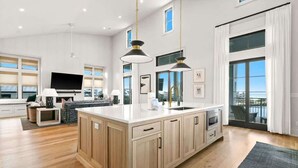 A spacious kitchen with a large island, wooden cabinets, and pendant lighting. - 283 Lakeview Drive (Seagrove Beach)