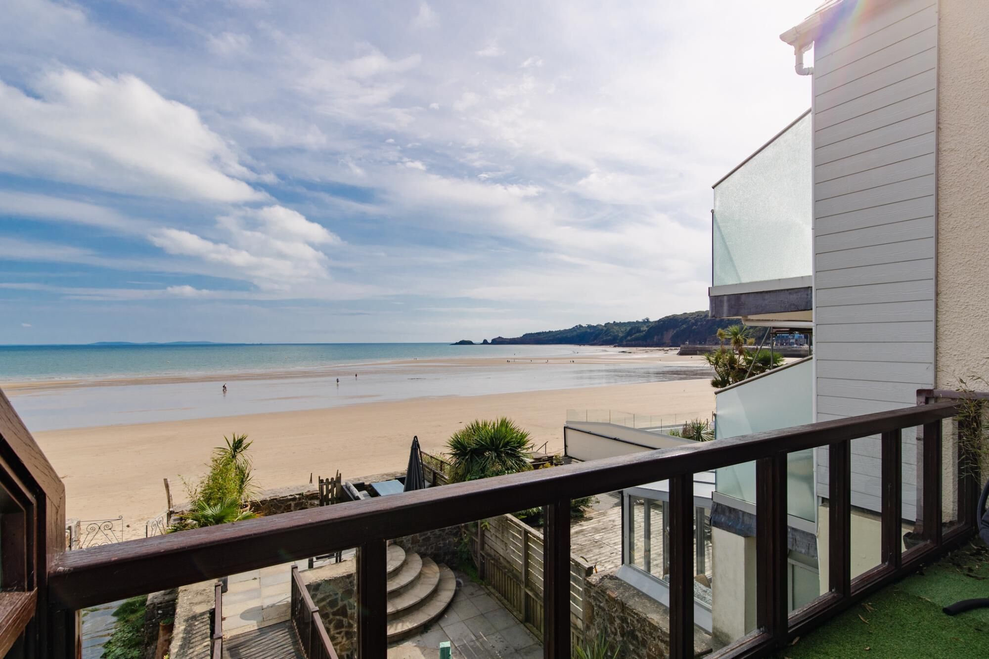 A balcony with a view of a beach and a modern building.