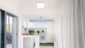 Cucina compatta con mobili bianchi, un piccolo bancone e una finestra che si affaccia sul verde.