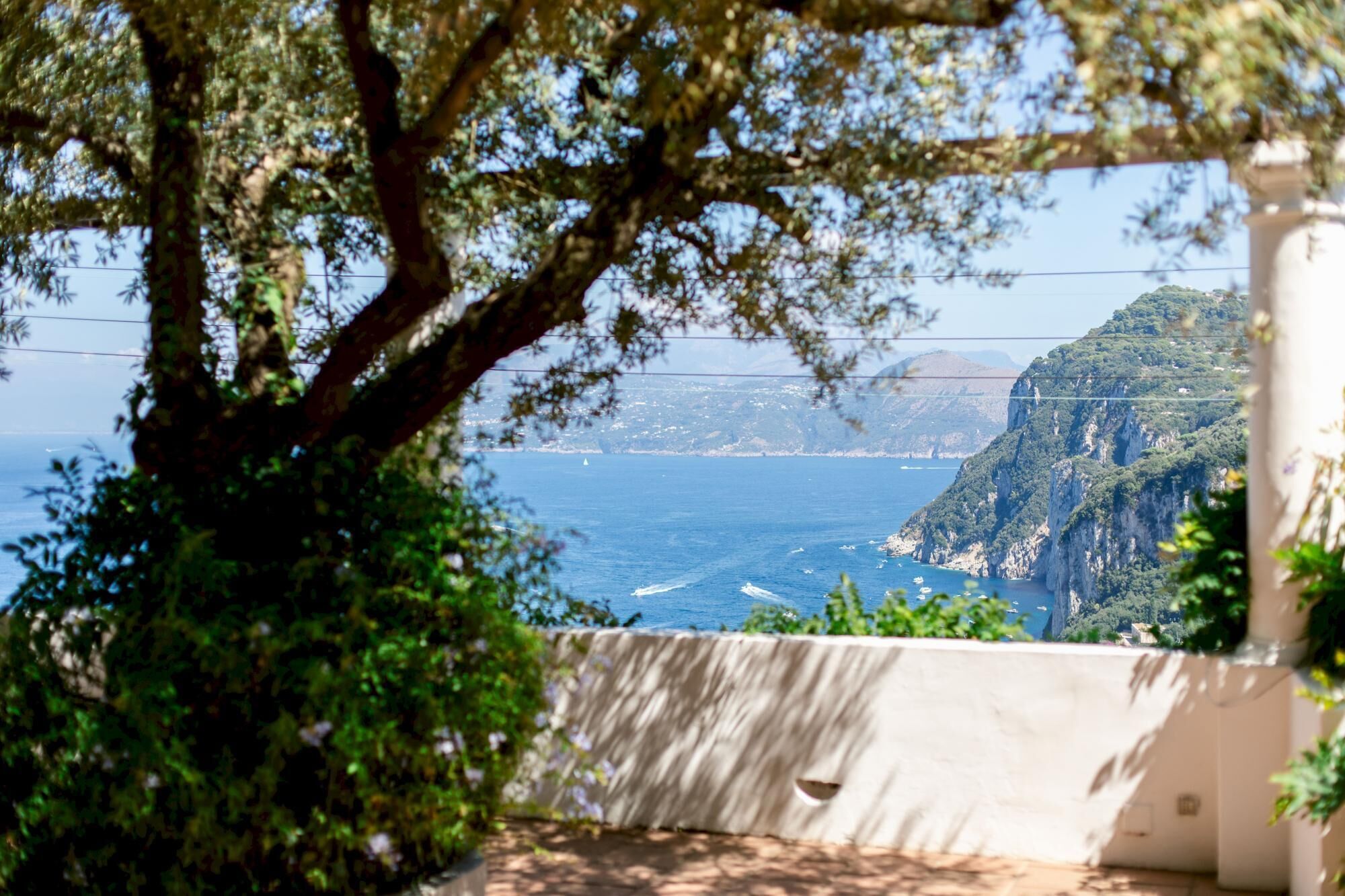 A coastal view with a cliff, sea, and a building with a white facade.