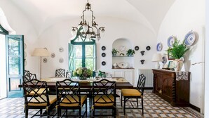 A dining area with a table set for six, surrounded by chairs with cushioned seats. - Villa Ginestra by Elite Villas (Capri)