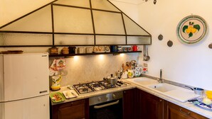 A kitchen with a gas stove, a sink, and a variety of kitchen utensils and cookware. - Villa Ginestra by Elite Villas (Capri)