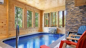Een houten chalet met een zwembad, grote ramen en buiten zitplaatsen.