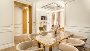 A dining area with a marble table, beige upholstered chairs, and a chandelier.