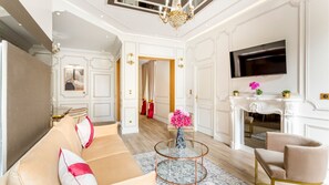 Een ruime woonkamer met een moderne bank, een ronde salontafel en een flatscreen televisie aan de muur.