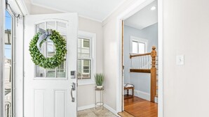A hallway leading to a staircase with a white door adorned with a wreath. - 5 Bedroom Historic Home minutes to Boston with Yard (Medford)