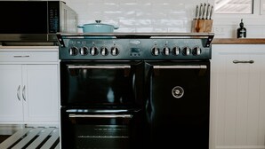 A kitchen with a black stove, a microwave, and a pot on the stove. - THE BILLOWS - BINALONG BAY.  Hamptons style escape overlooking the Bay of Fires. (Binalong Bay)