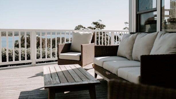 A balcony with wicker furniture, a wooden table, and a view of the sea. - THE BILLOWS - BINALONG BAY.  Hamptons style escape overlooking the Bay of Fires. (Binalong Bay)
