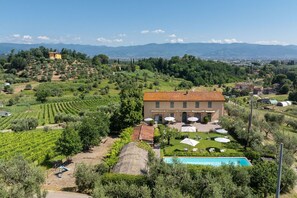 A villa with a swimming pool, outdoor seating, and vineyard views.