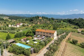 A villa with a swimming pool, surrounded by vineyards and a mountainous backdrop.