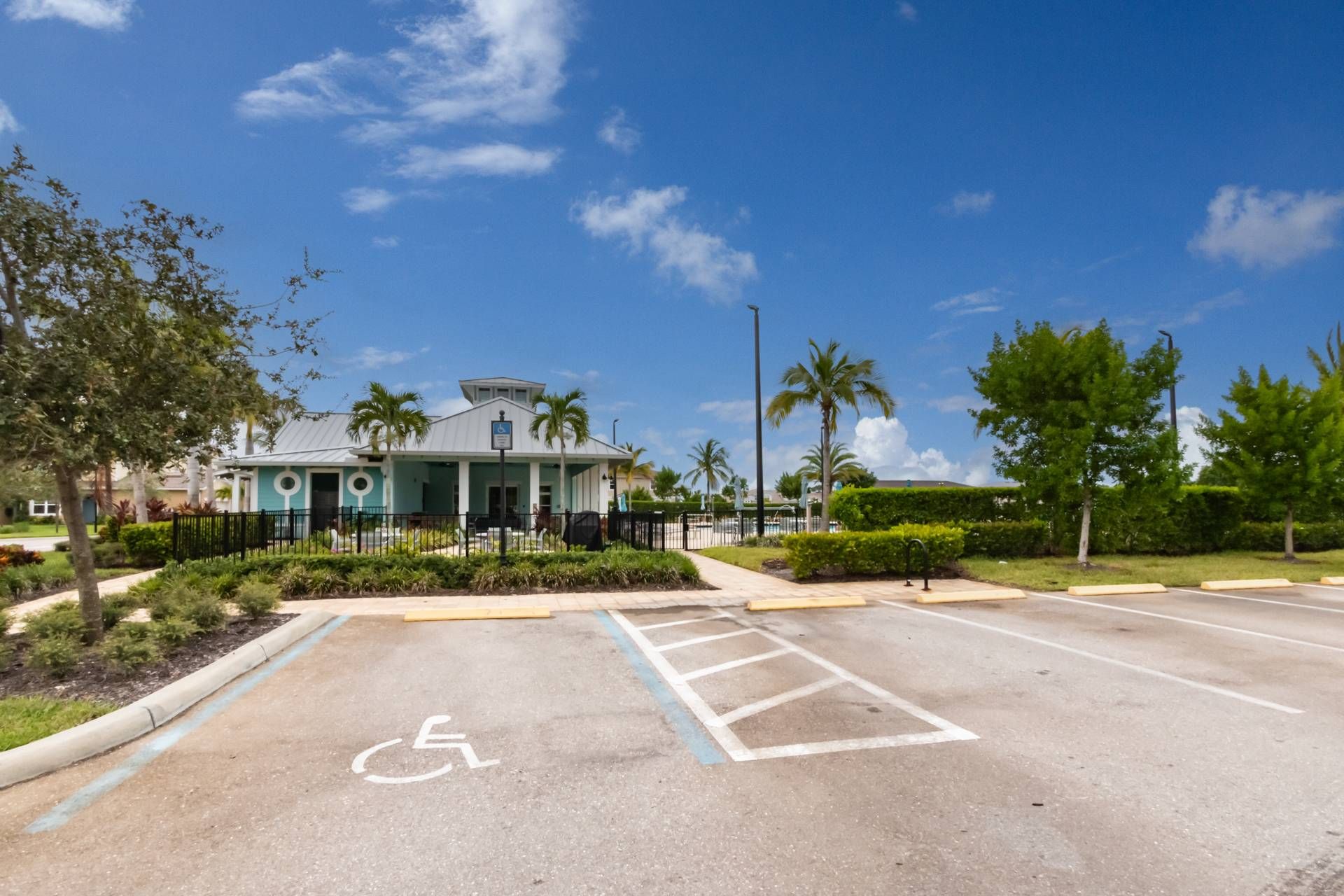 A parking lot with a handicapped parking space, a building with a blue facade, and palm trees.