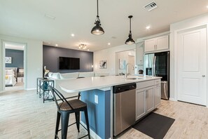 A modern kitchen with a central island, stainless steel appliances, and pendant lighting.
