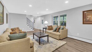 A living room with beige sofas, a coffee table, and a lamp. There is a staircase leading to another room. - Tranquil retreat in Fairfax: your home away from home (Fairfax)