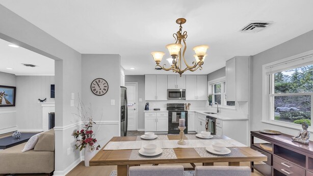 A modern kitchen with white cabinets, a central island, and a dining area with a wooden table and chairs. - Tranquil retreat in Fairfax: your home away from home (Fairfax)