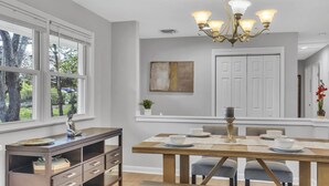 A modern dining area with a wooden table, chairs, and a chandelier. - Tranquil retreat in Fairfax: your home away from home (Fairfax)