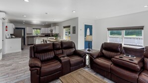 A modern living room with leather sofas, a wooden coffee table, and a view of the backyard through a window. - Amber Nook! Always clean, and build to be comfortable! (The Dalles)