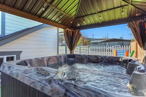 A hot tub with a metal roof and a white picket fence in the background.