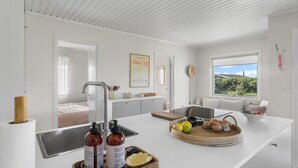 A modern kitchen with white cabinetry, a large window, and a view of the outdoors. - "Iven" - 140m from the sea by Interhome (Otterup)