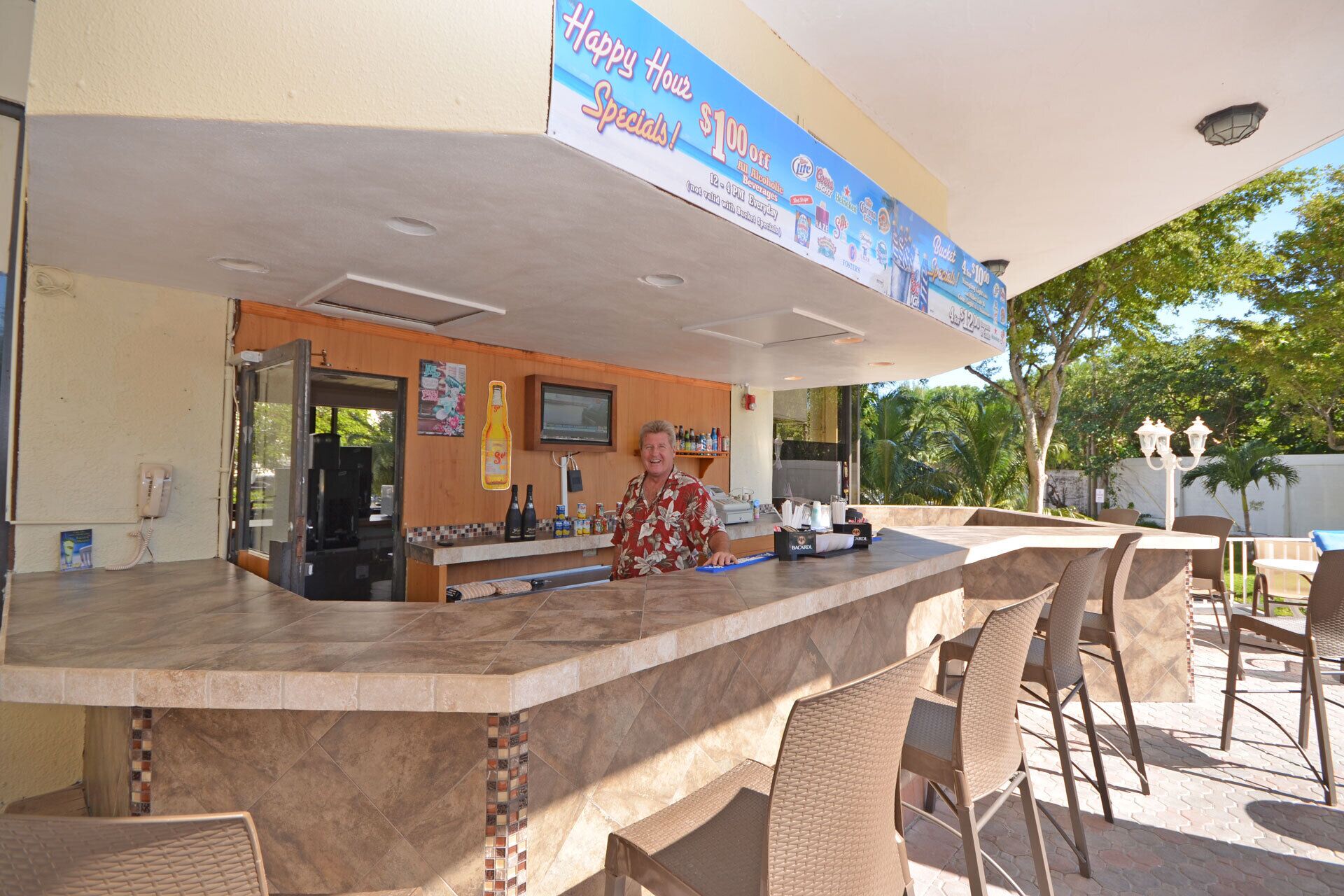 An outdoor bar area with a counter, bar stools, and a sign advertising specials.