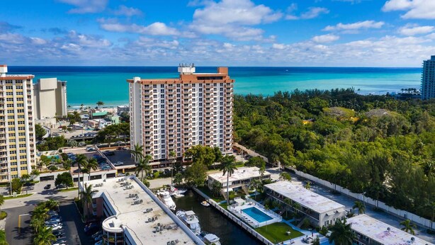 A high-rise hotel with multiple floors, a marina with boats, and a clear view of the ocean. - Prime Central Beach Location! 2BR Condo, Pool, Bar, Game Room, at Fort Lauderdale Beach Resort (Fort Lauderdale)