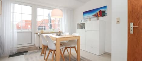 Una cocina moderna con armarios blancos, una mesa de comedor de madera y un cuadro sobre los armarios.
