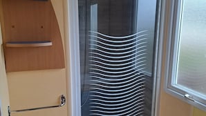 A bathroom with a shower enclosure, a toilet, and a sink. - Joli Mobil Home sur Camping (Enquin sur baillons)