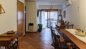A dining area with a long wooden table, chairs, and a potted plant. - Cosy Local Artist's Flat, Central Location, Fully Equipped (Córdoba)