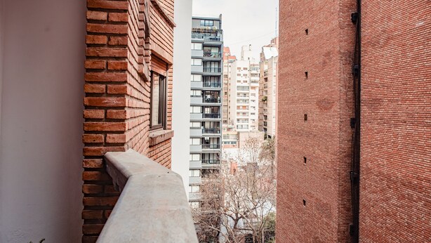A narrow alleyway between two brick buildings with a balcony overlooking a street with parked cars and a tree. - Cosy Local Artist's Flat, Central Location, Fully Equipped (Córdoba)
