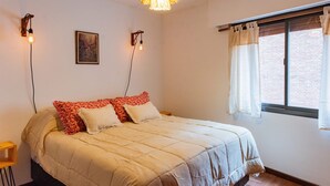 A bedroom with a bed, two wall-mounted light fixtures, a picture on the wall, and a window with curtains. - Cosy Local Artist's Flat, Central Location, Fully Equipped (Córdoba)