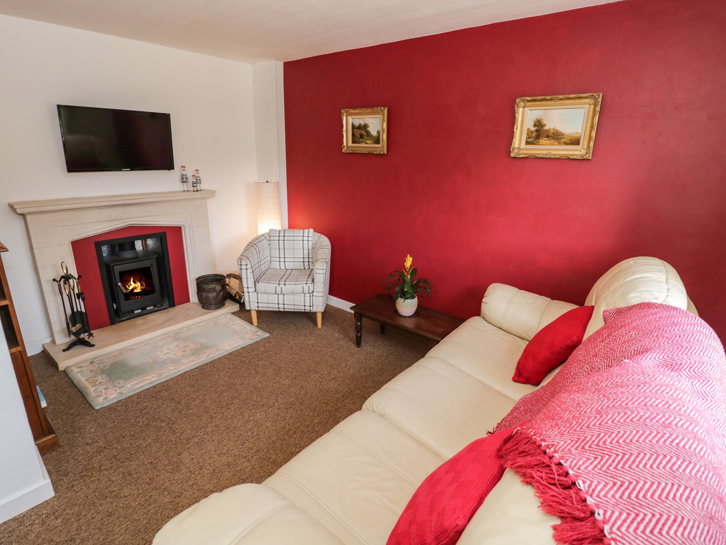A living room with a fireplace, a sofa, a chair, and two framed pictures on the wall.