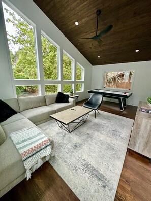 Un salon moderne avec un canapé, une table basse et une table de billard.