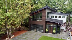 A modern two-story house with a garage, a well-maintained lawn, and a stone pathway leading to the entrance. - Brand new! Modern Lake Whatcom View home (Bellingham)