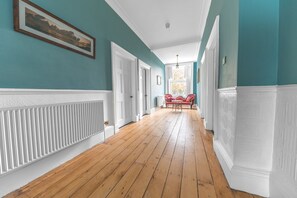 Un couloir doté d’un plancher en bois, de lambris blancs et de murs de couleur turquoise.