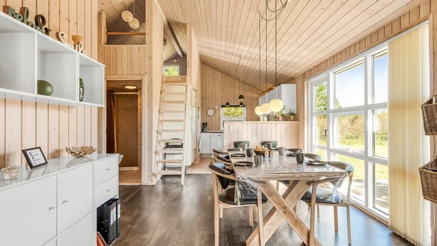 Una cucina moderna con mobili in legno, un tavolo da pranzo e ampie finestre.