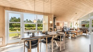 Un'ampia zona giorno con un grande soffitto in legno, un tavolo da pranzo con sedie e un camino.
