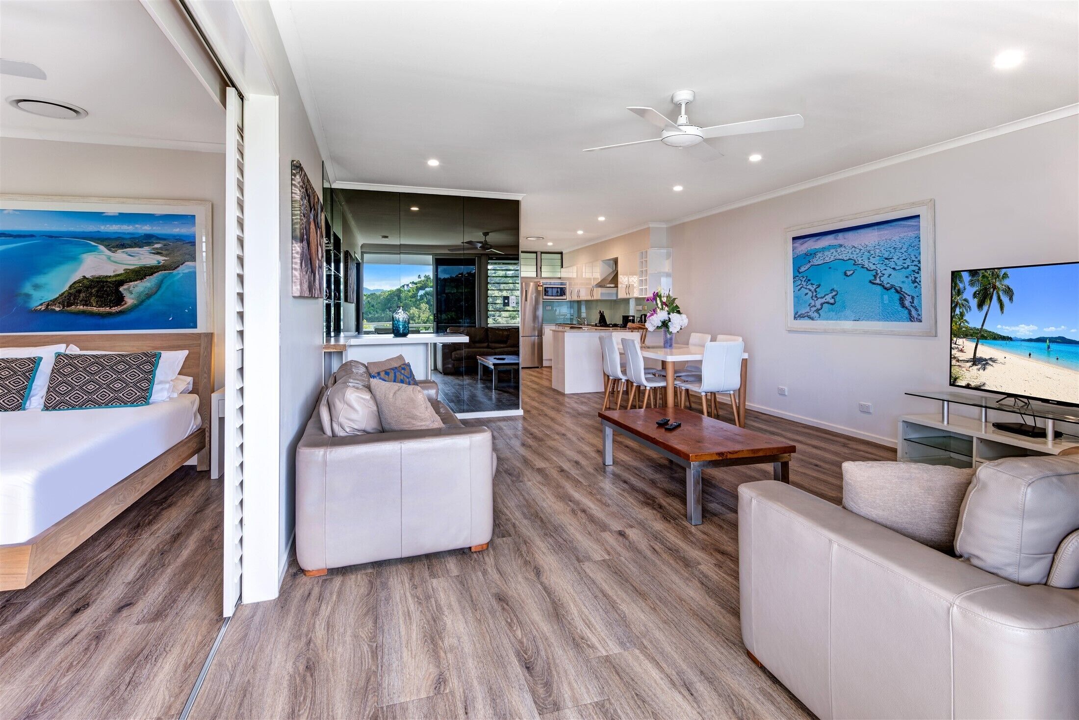 A modern living room with a sofa, a dining table, and a kitchen in the background.