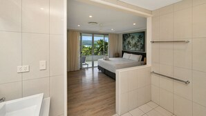 Ett modernt hotellrum med en stor säng, ett badrum med badkar och utsikt över omgivningarna.