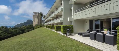 A modern hotel with a flat roof, multiple balconies, and a well-maintained lawn.