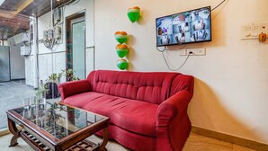 Un sofá rojo, una mesa de centro de vidrio y un televisor de pared que muestra varias imágenes de cámaras de seguridad.