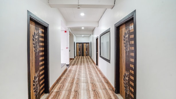 Un pasillo con puertas de madera, suelo estampado e iluminación empotrada en el techo.