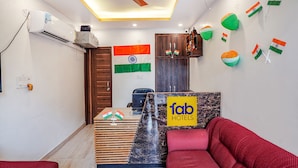 Habitación de hotel con mostrador de recepción, ventilador de techo, unidad de aire acondicionado y una bandera en la pared.
