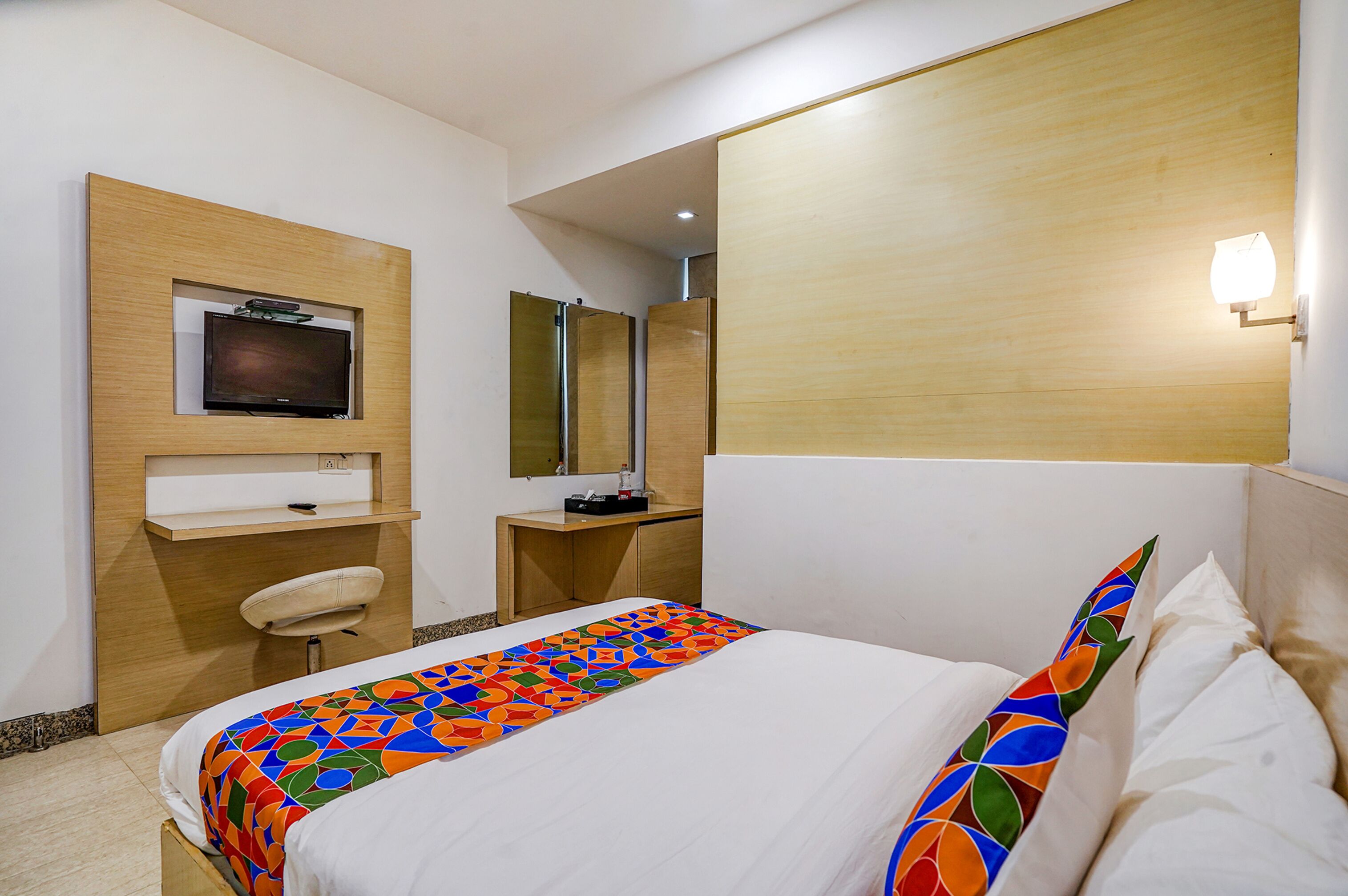 A hotel room with a bed, a desk, a television, and a mirror.