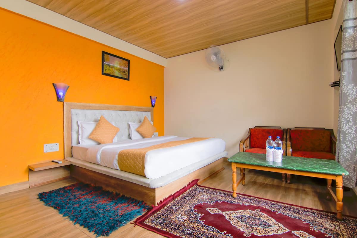 Ein Schlafzimmer mit einem Bett, einem Nachttisch, einem Tisch mit Flaschen und einem Sofa.