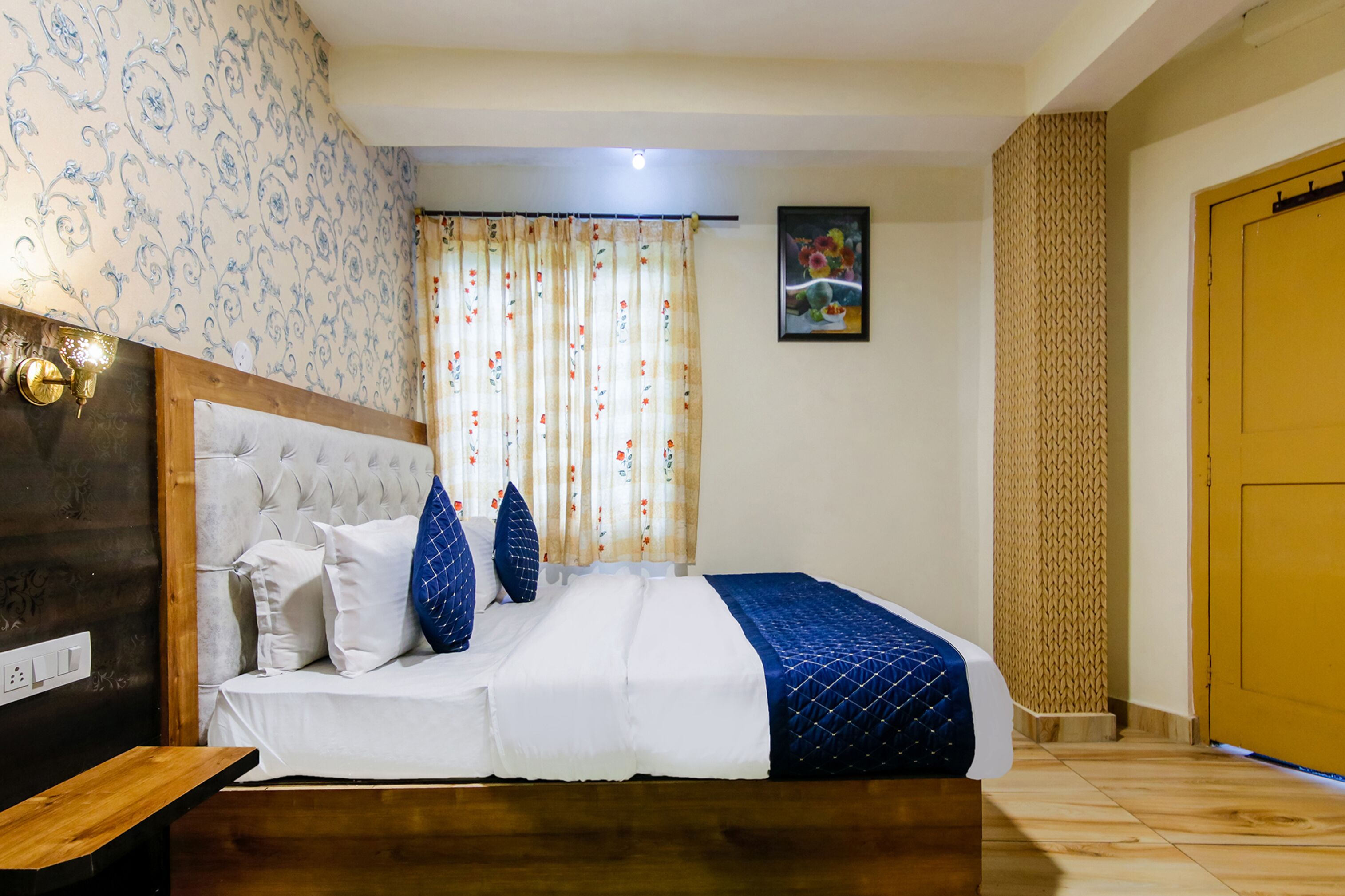 A neatly arranged bedroom with a bed, a wooden headboard, a nightstand, and a painting on the wall.
