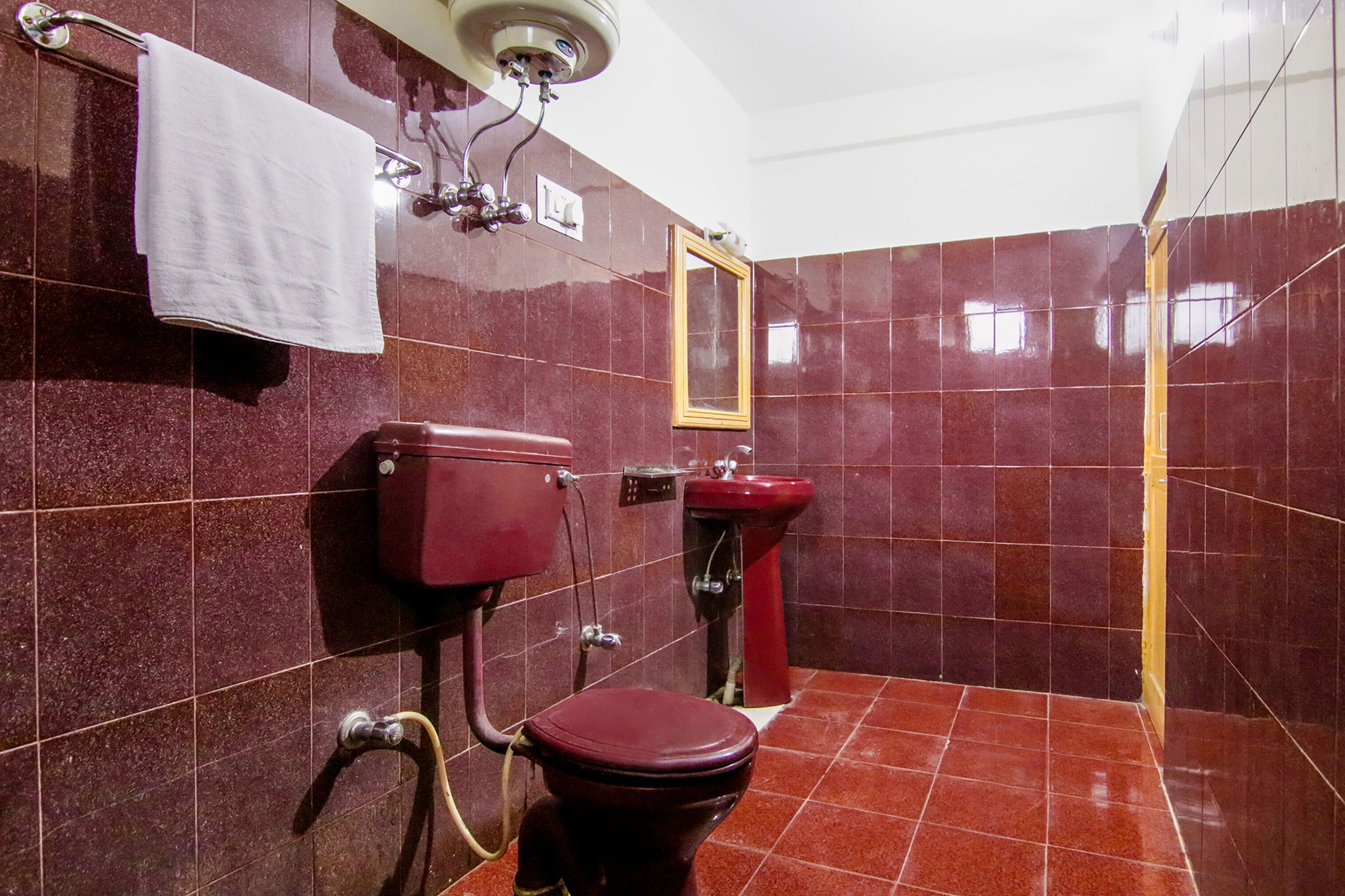 A bathroom with a red toilet, a red sink, and a mirror on the wall.