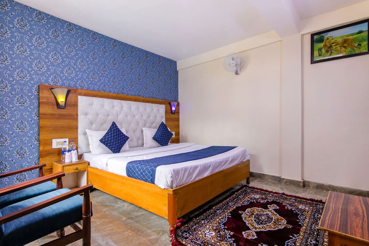 Ein ordentlich eingerichtetes Schlafzimmer mit einem hölzernen Bett, einem Nachttisch, einem Stuhl und einem gemusterten Teppich.